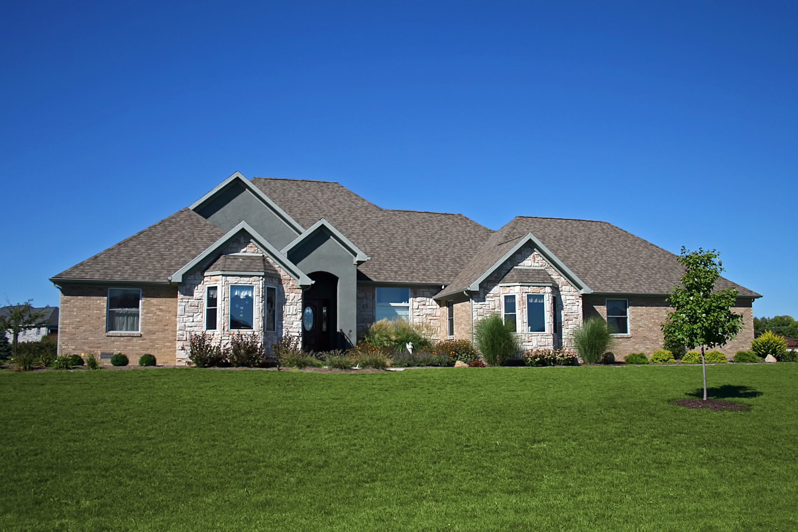 Small town square with neatly mowed grass, trees, and historic storefronts, featuring a vibrant painted shoe advertisement mural. 